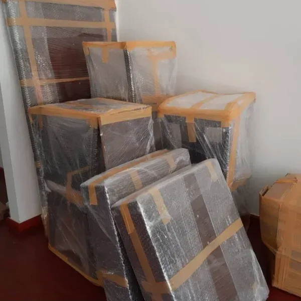 Multiple furniture pieces wrapped in bubble wrap and tape ready for moving